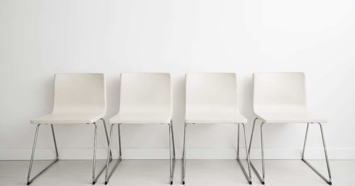 Waiting area: Four plain white chairs in a minimalist setting.